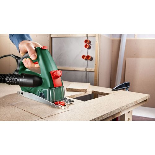 Grüner Bosch Stichsäge schneidet Holzplatte, Hand hält Werkzeug. Werkstatt.