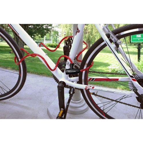 Una bicicletta bianca è assicurata con un lucchetto a cavo rosso fissato a un palo.