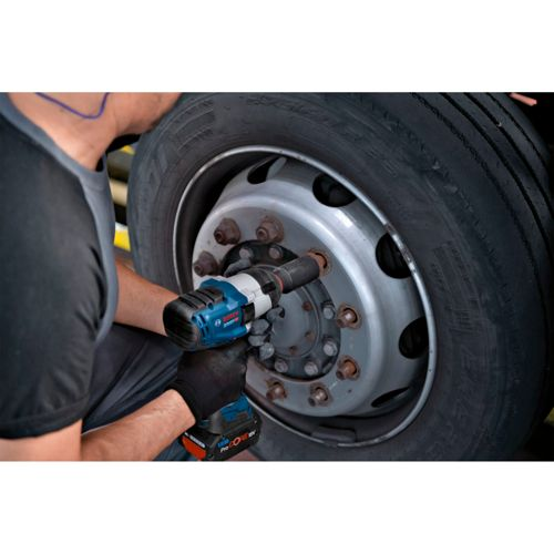 Un hombre usa una llave de impacto Bosch azul para aflojar un perno de una rueda.