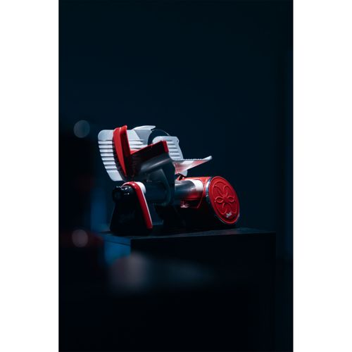 Ein roter und weißer Fleischschneider auf einem dunklen Podest.