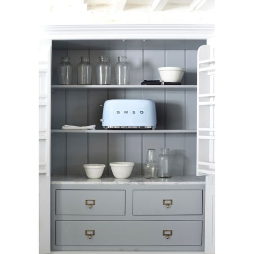 Ein hellblauer Smeg-Toaster steht in einem offenen grauen Schrank neben Glasflaschen und Schüsseln.