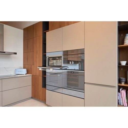 Moderne Küche mit Holz- und beigen Schränken, eingebauten Geräten und einem blauen Toaster.