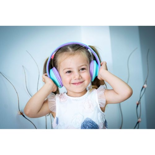 Una bambina con le codine sorride, indossando cuffie colorate blu, viola e rosa, contro una parete azzurra.