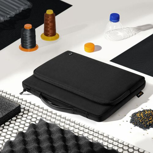 Schwarze Laptoptasche mit Garnrollen, Orangendose, Flasche und Schaumstoff.