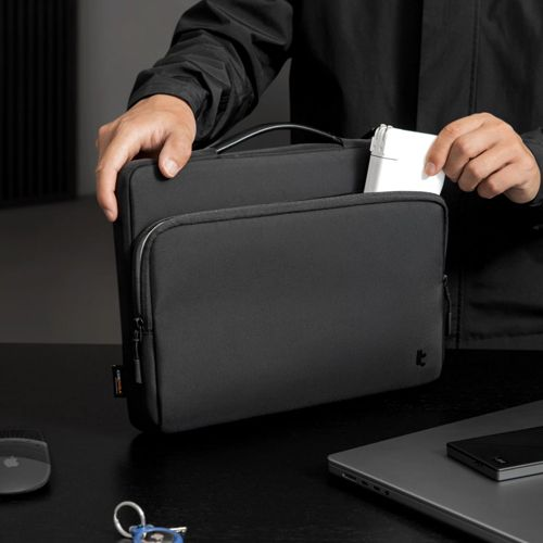 Eine Person legt eine weiße Box in eine schwarze Laptoptasche.