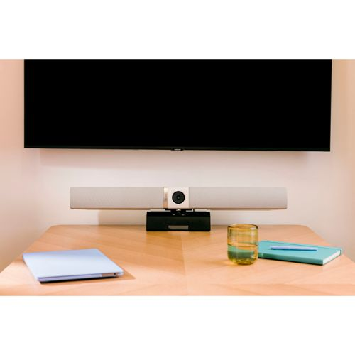 Ein Konferenz-Lautsprecherbalken unter einem Fernseher auf einem Holztisch.