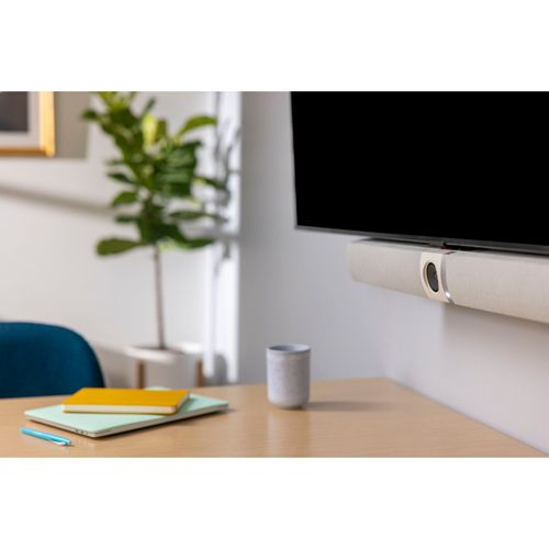 Ein wandmontierter Fernseher mit Soundbar sitzt über einem Holztisch mit Notizbüchern und einer Tasse.