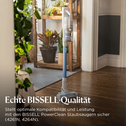 Un aspirapolvere BISSELL si trova in una stanza con piante e pavimenti in legno.