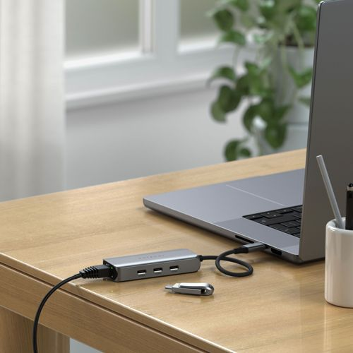 Un hub USB argentato con un laptop e un'unità USB su una scrivania di legno.