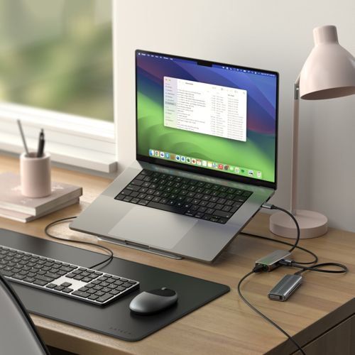 Un laptop con dispositivi esterni su una scrivania di legno. Tastiera e mouse in primo piano.