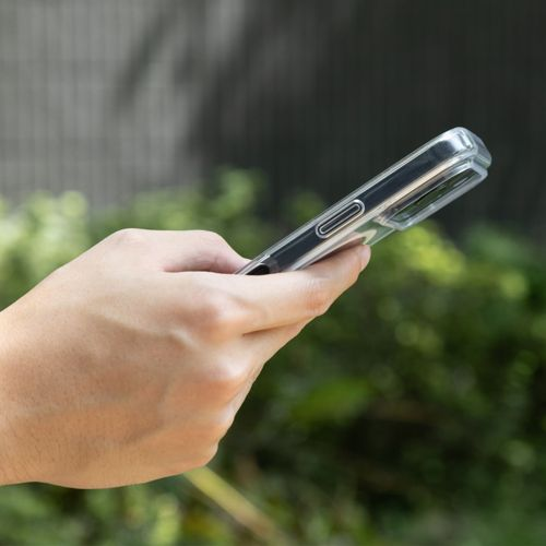 Una mano tiene uno smartphone con custodia trasparente all'aperto.