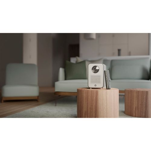 Ein weißer Projektor mit Fernbedienung steht auf einem Holztisch in einem Wohnzimmer.