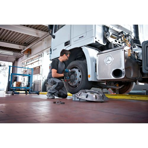Mechanik naprawia oponę ciężarówki w warsztacie z narzędziami.