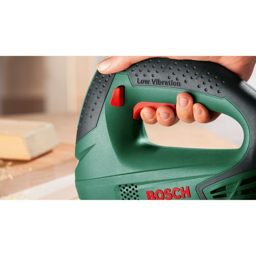 Hand houdt groene Bosch decoupeerzaag met rode trekker vast. Tekst 'Low Vibration'.
