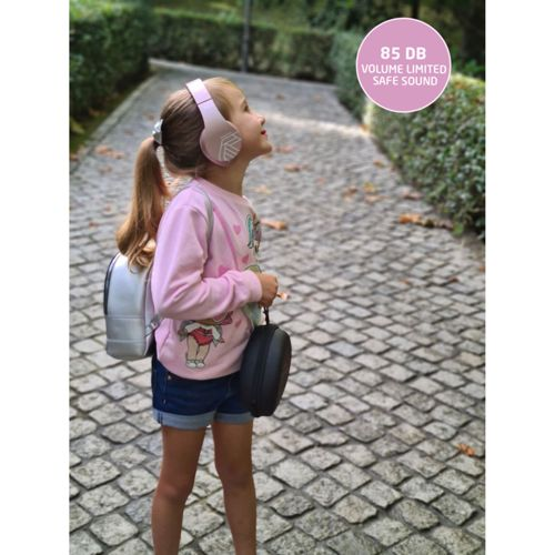 Bambina con cuffie e zaino su un sentiero acciottolato.