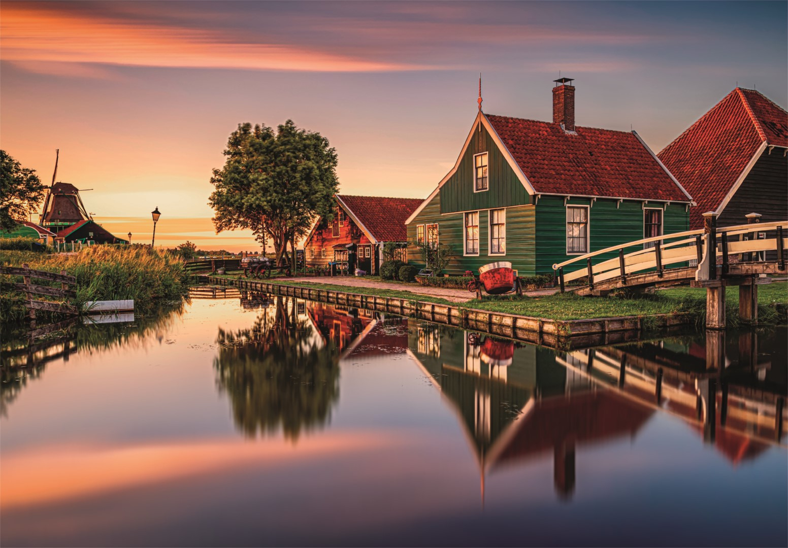 Case sul canale con mulino al tramonto. Riflessi sull'acqua.