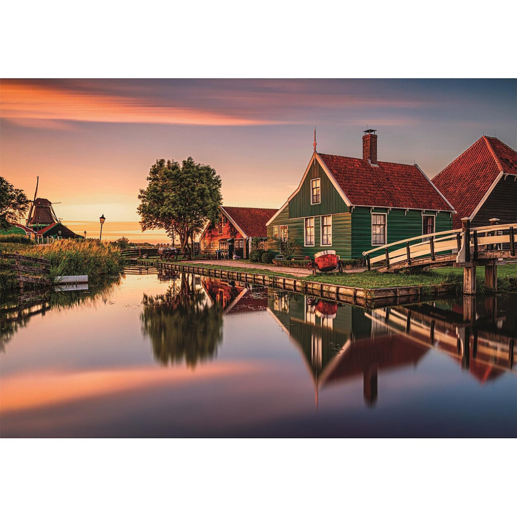 Villaggio olandese al tramonto: mulino, canale, case verdi tetti rossi, riflessi.