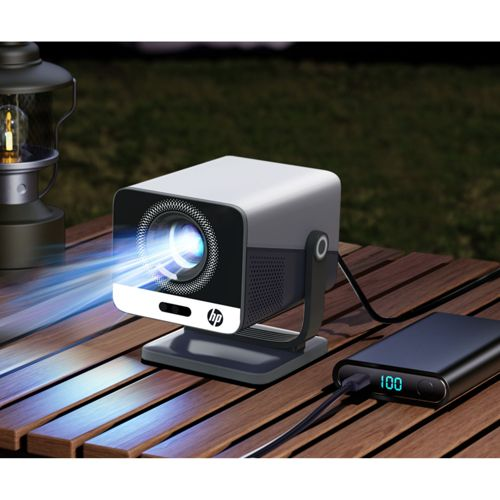 Ein HP-Projektor projiziert blauen Lichtstrahl auf einen Holztisch, neben einer Laterne und Powerbank.