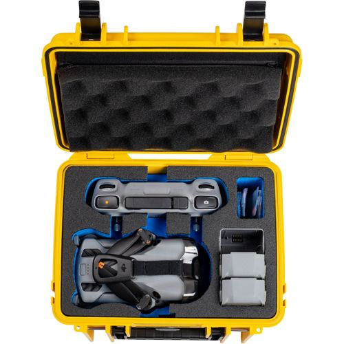 Una custodia gialla contiene un drone grigio, un controller e batterie, il tutto fissato da schiuma.