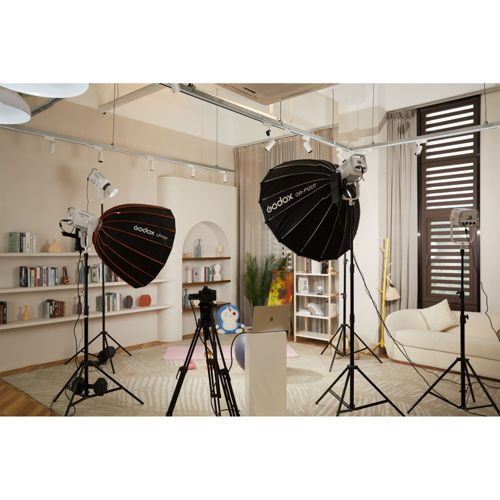 Ein Studioaufbau mit Softbox-Leuchten, Stativ, Laptop und Regalen.