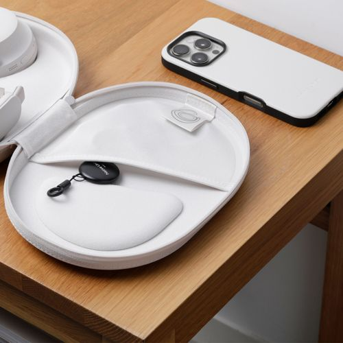 Weißes iPhone und offene weiße Hülle mit schwarzem Tracker auf Holztisch.