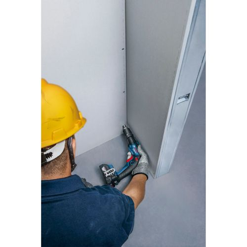 Ein Mann mit gelbem Helm bohrt mit einem blauen Akkuschrauber in eine Wand.