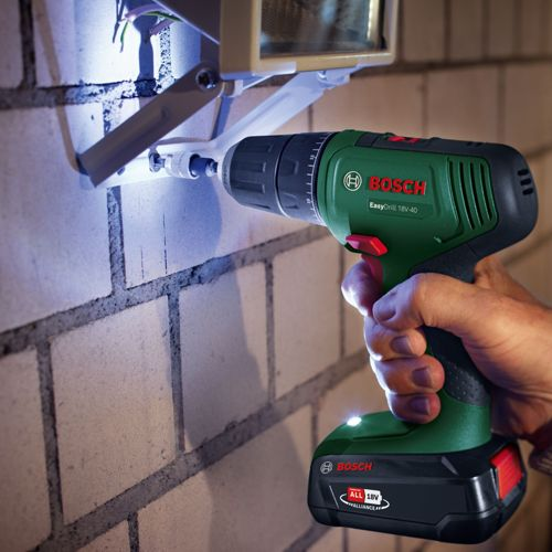 Un trapano avvitatore a batteria Bosch viene utilizzato per fissare una staffa a un muro di mattoni.