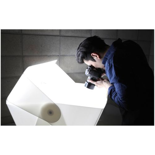 Ein Mann fotografiert mit einer Kamera einen weißen Lichtkasten.