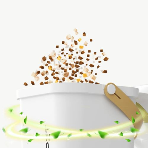 Piccoli pezzi marroni e bianchi volano fuori da un contenitore bianco, circondato da foglie verdi.