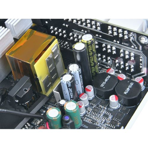 Close-up van een printplaat met veel elektronische componenten zoals condensatoren en een transformator.