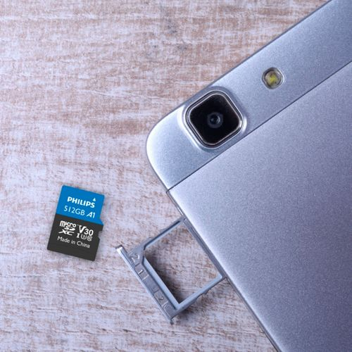 Eine silberne Speicherkarte liegt neben einem Smartphone-Schacht.