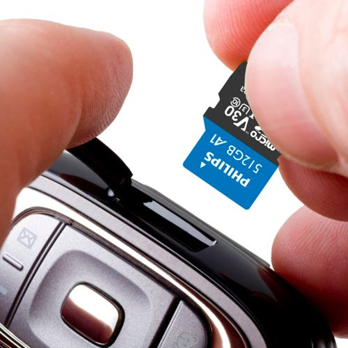 Eine Hand steckt eine Philips 512GB MicroSD-Karte in ein Gerät.