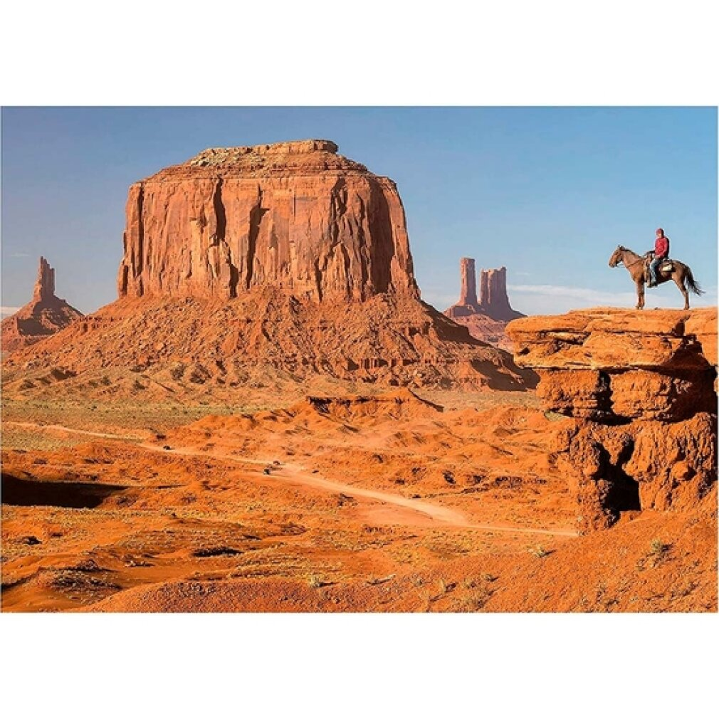 Vaquero a caballo en un acantilado con vistas a las formaciones rocosas rojas de Monument Valley.