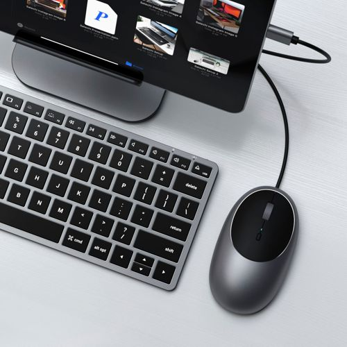 Un ratón y teclado de computadora grises sobre un escritorio blanco junto a una tableta.
