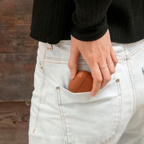 Eine Hand steckt eine braune Hülle in die Gesäßtasche einer hellblauen Jeans.