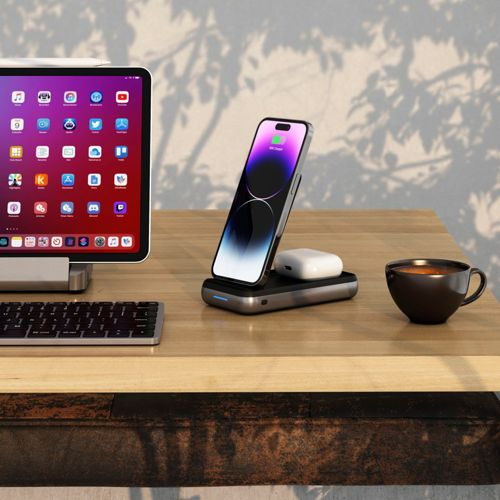 Un escritorio moderno con tablet, teléfono cargando, auriculares y taza de café.