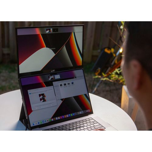 Un laptop con due schermi all'aperto, una persona in primo piano.