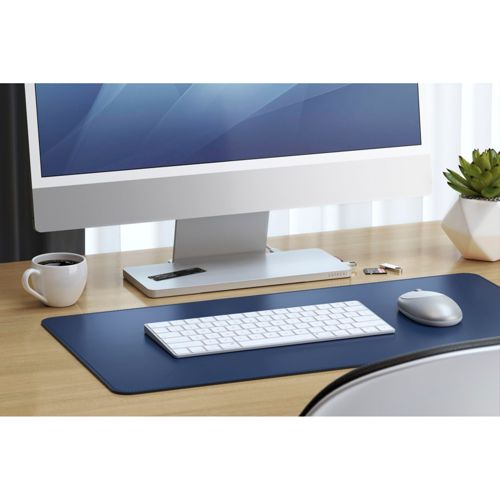 Una scrivania con computer, tastiera, mouse, tazza da caffè e pianta.