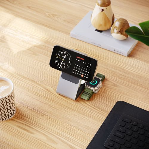 Ein Handy und eine Smartwatch auf einem Ladeständer auf einem Holztisch.