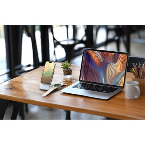 Un laptop, telefono e smartwatch su un tavolo di legno con piante e tazza.