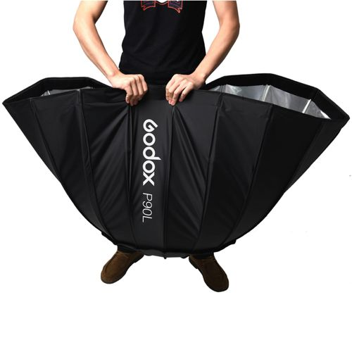 Eine Person hält einen großen, schwarzen Godox P90L Softbox-Reflektor.