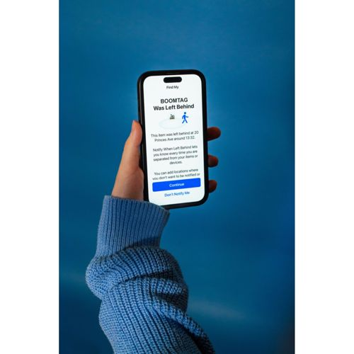 Una mano tiene uno smartphone con il messaggio 'BOOMTAG è stato lasciato' su sfondo blu.