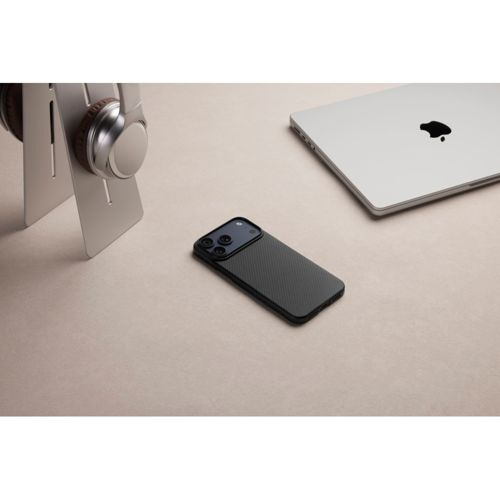 Un iPhone negro, auriculares plateados y un portátil descansan sobre una superficie beige.