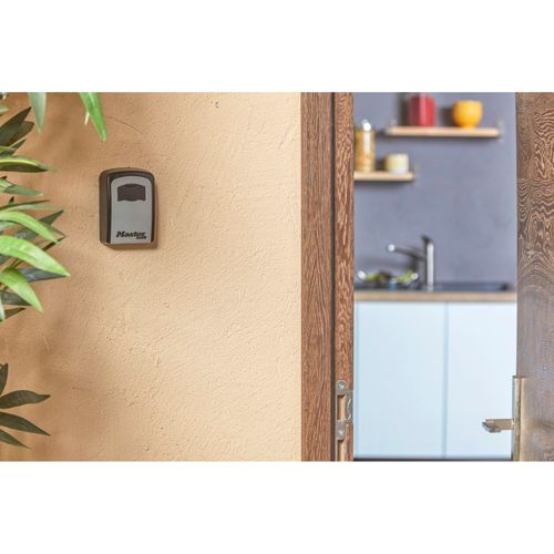 Un portallaves Master Lock está montado en una pared beige, junto a una puerta abierta.