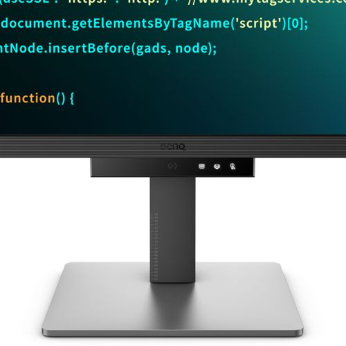 A monitor displays code on screen, with a silver stand below.