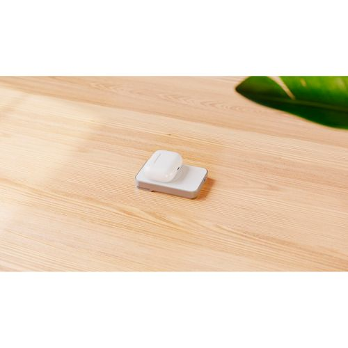 Ein weißes kabelloses Ladeetui für Ohrhörer liegt auf einer weißen kabellosen Ladestation auf einem Holztisch.