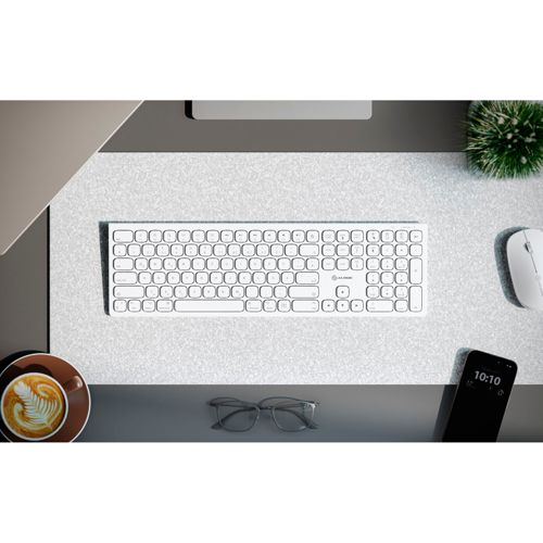 Tastiera bianca, mouse, occhiali, caffè e telefono su una scrivania.