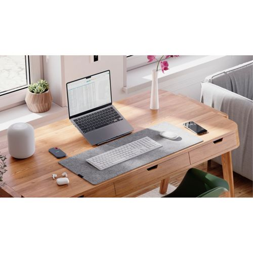 Una scrivania con laptop, tastiera, mouse, cuffie e telefono.