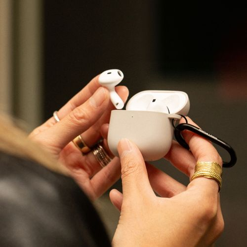 Mani inseriscono un auricolare wireless bianco in una custodia di ricarica grigio chiaro con clip nera.