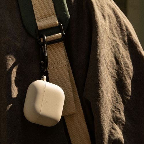 Una custodia beige chiaro per auricolari pende da una tracolla.